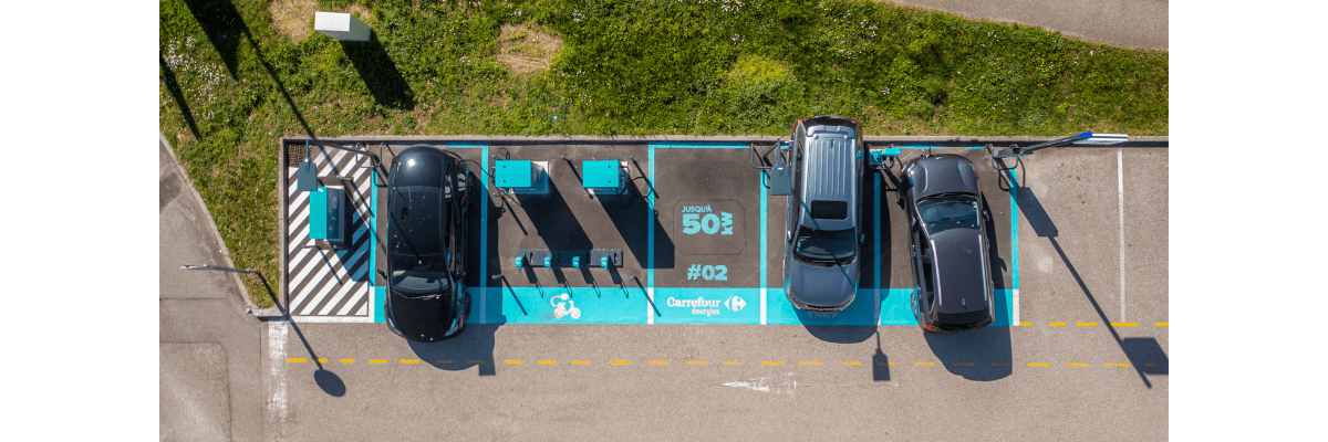 Vue aérienne d'une station DRIVECO Carrefour Energies, avec 3 véhicules stationnés en recharge.