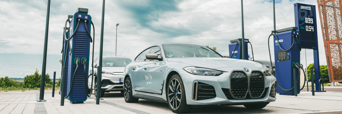 Une BMW I4 100% électrique est garée sur un emplacement pour se recharger sur une borne de recharge DRIVECO
