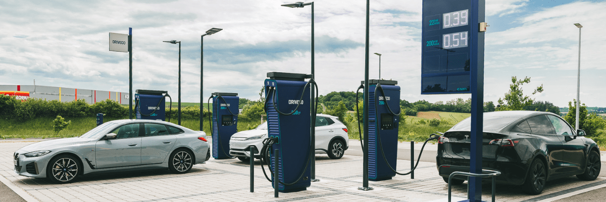 Plusieurs véhicules 100% électriques sont garés sur des emplacements pour se recharger dans une station de recharge DRIVECO
