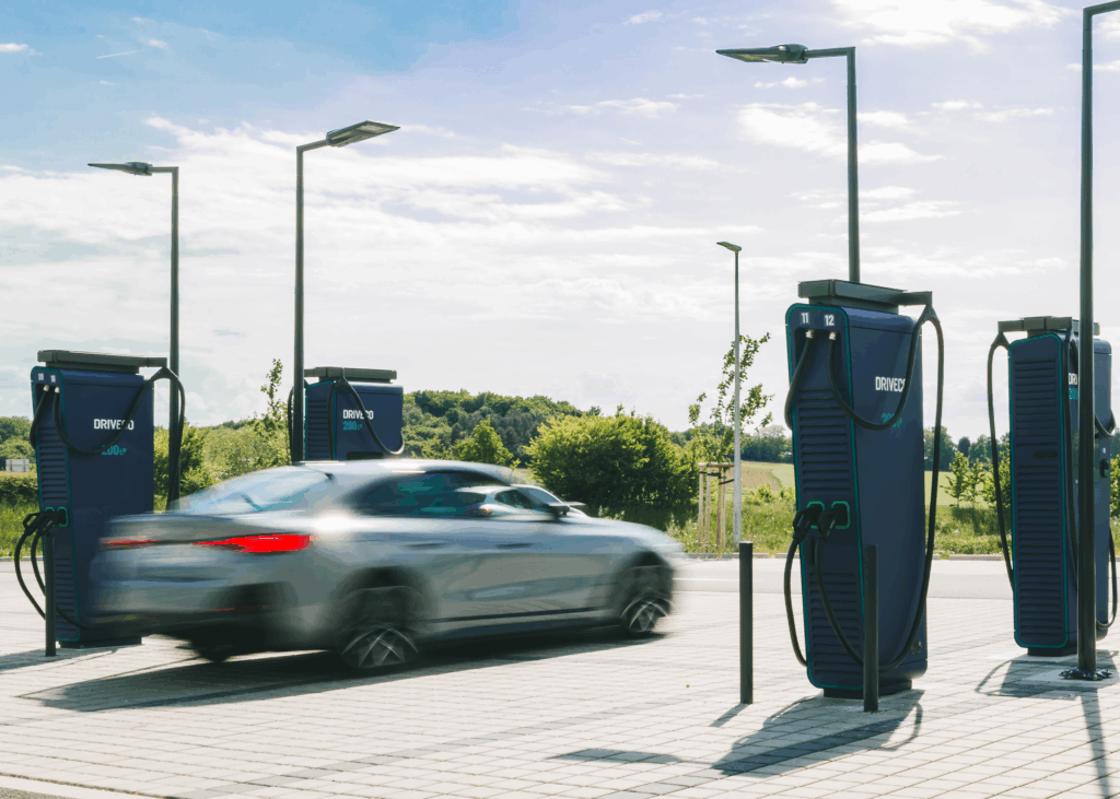 Une voiture électrique passe devant une station de recharge DRIVECO pour véhicules 100% électriques