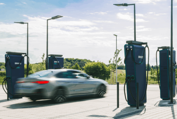 Une voiture électrique passe devant une station de recharge DRIVECO pour véhicules 100% électriques