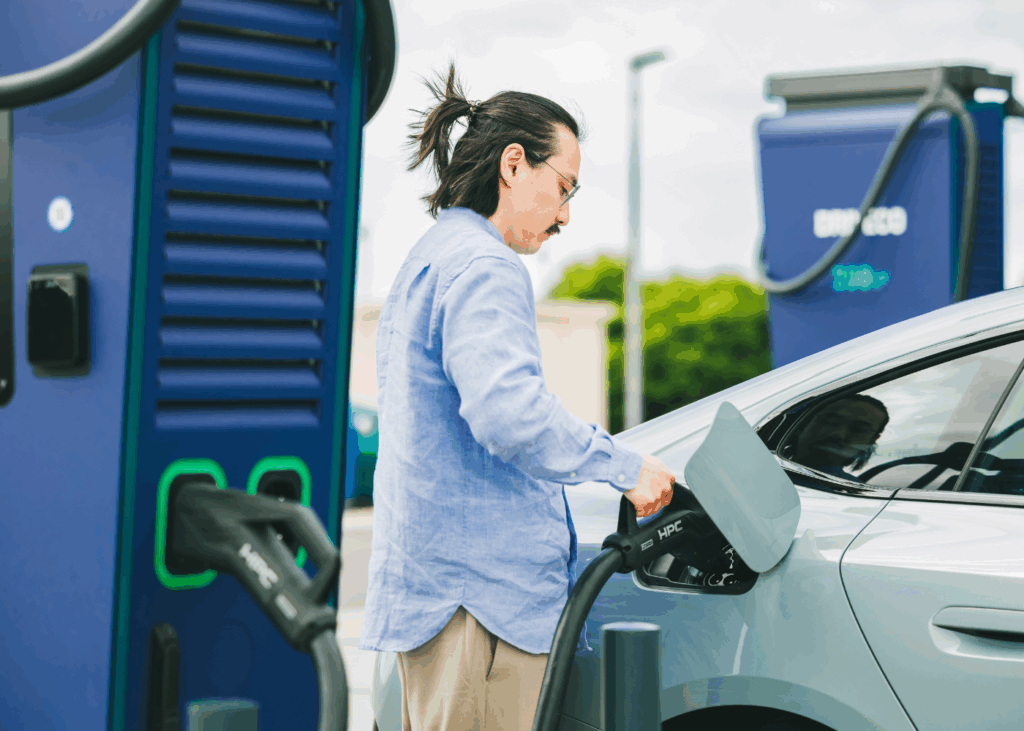 Un utilisateur de véhicule électrique branche un connecteur d'une station de recharge DRIVECO sur sa voiture.
