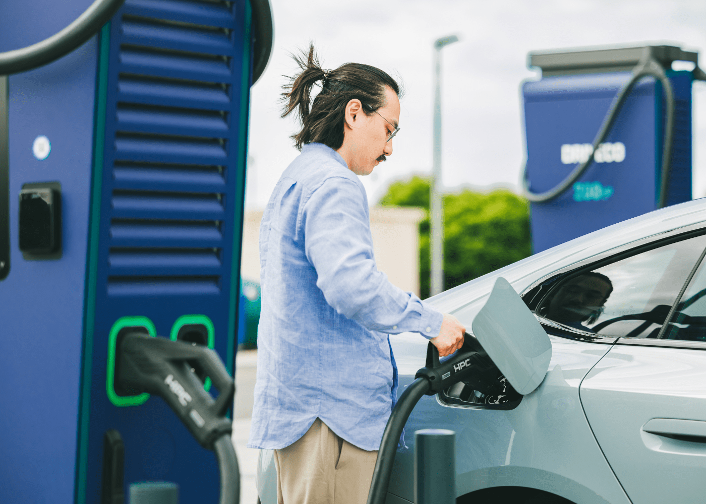 Un utilisateur de véhicule électrique branche un connecteur d'une station de recharge DRIVECO sur sa voiture.