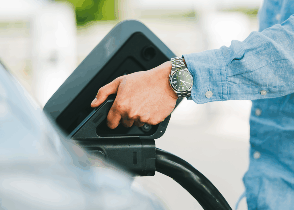 Une main est en train de brancher une voiture électrique pour une recharge.