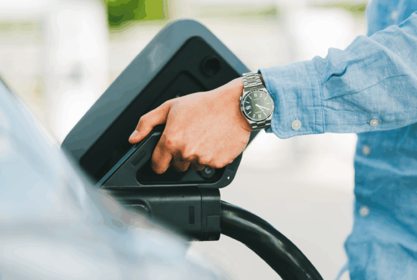 Une main est en train de brancher une voiture électrique pour une recharge.