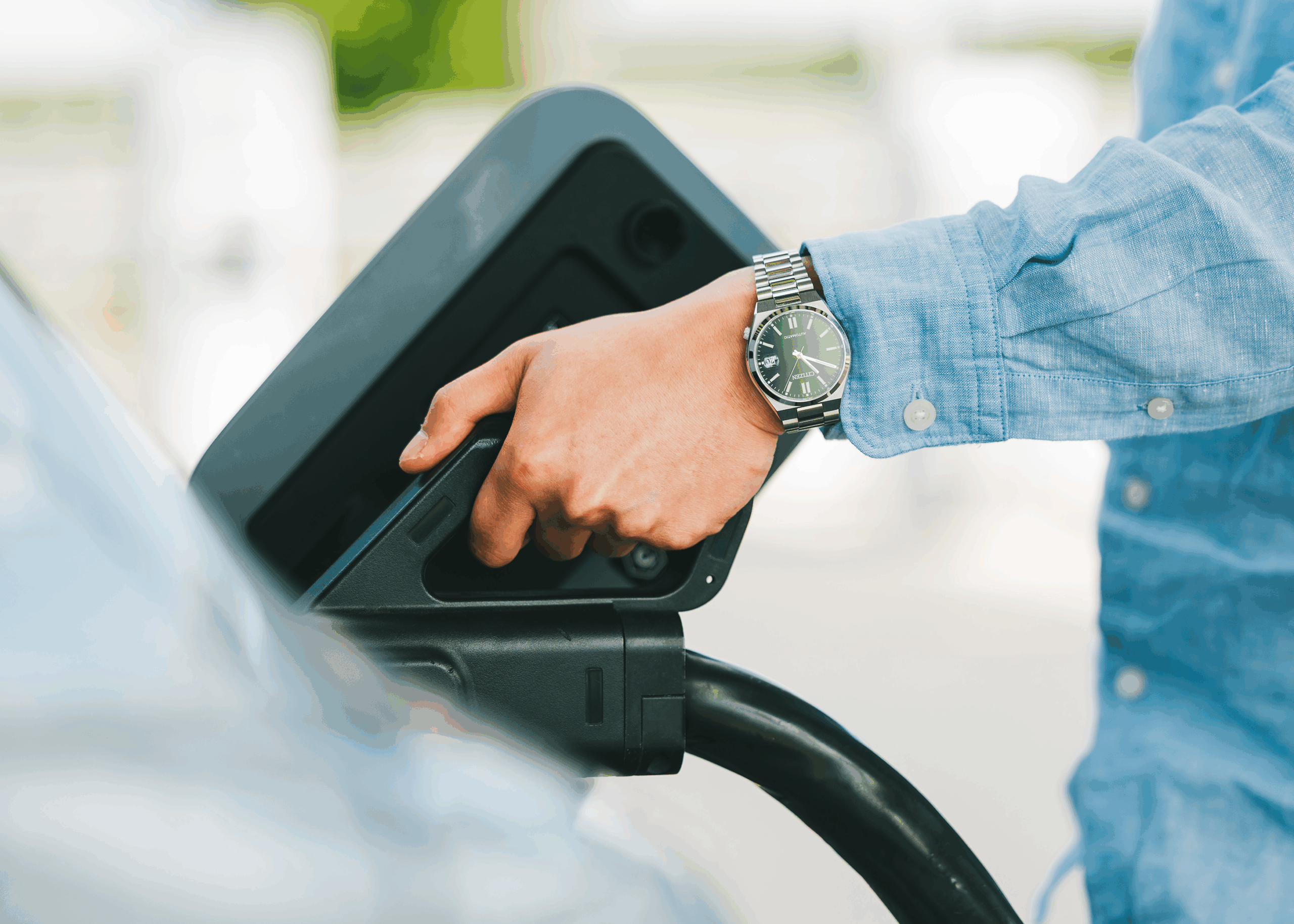 Une main est en train de brancher une voiture électrique pour une recharge.