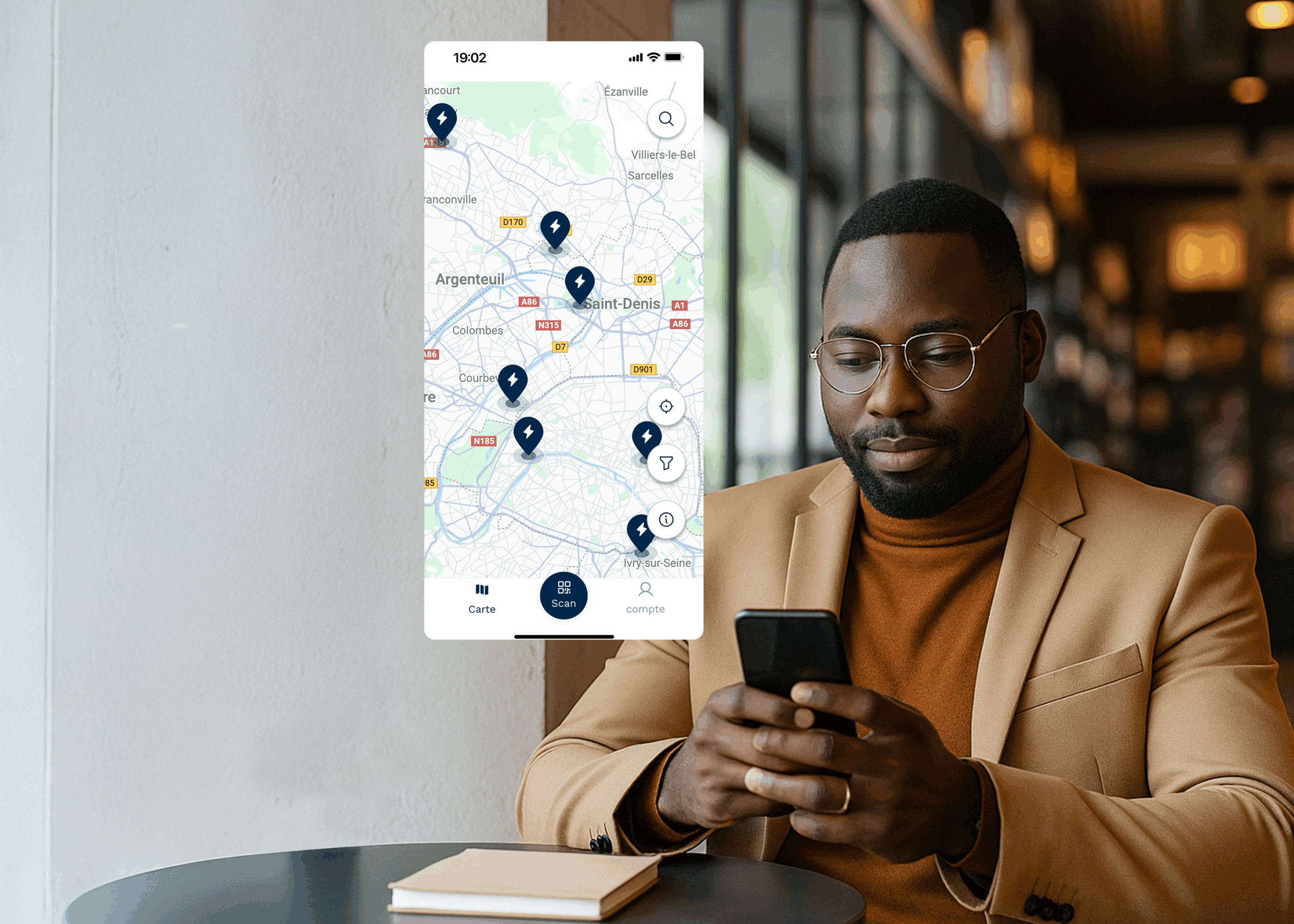 Un utilisateur tient son téléphone dans la main, le visuel affiche ce qu'il se passe sur son écran, une carte virtuelle avec des points indiquant des stations de recharge électrique.