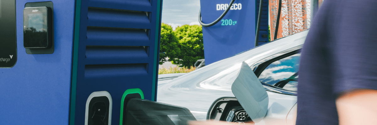 Gros plan sur une borne de recharge rapide DRIVECO de 200 kW, connectée à une voiture électrique grise en cours de charge.
