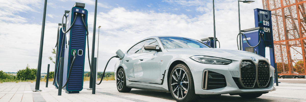 Une voiture électrique BMW grise en cours de recharge sur une station DRIVECO moderne.