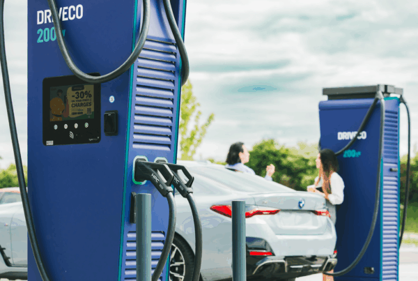 Bornes de recharge rapides DRIVECO 200 kW en fonctionnement, avec un véhicule électrique branché et deux personnes discutant à proximité sur un parking en plein air.