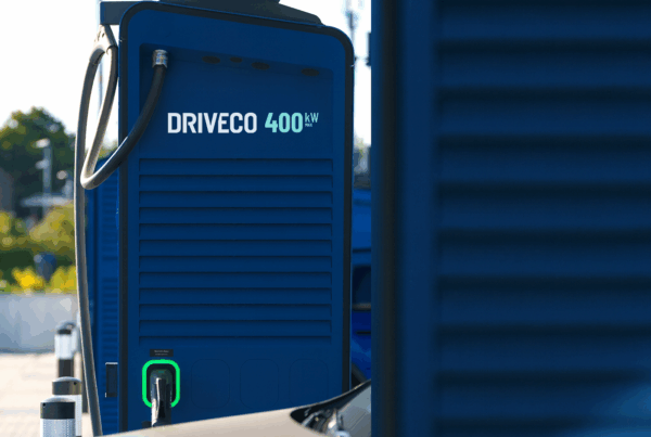 Borne de recharge rapide DRIVECO en gros plan, avec connecteur branché à un véhicule électrique sur un parking en extérieur.