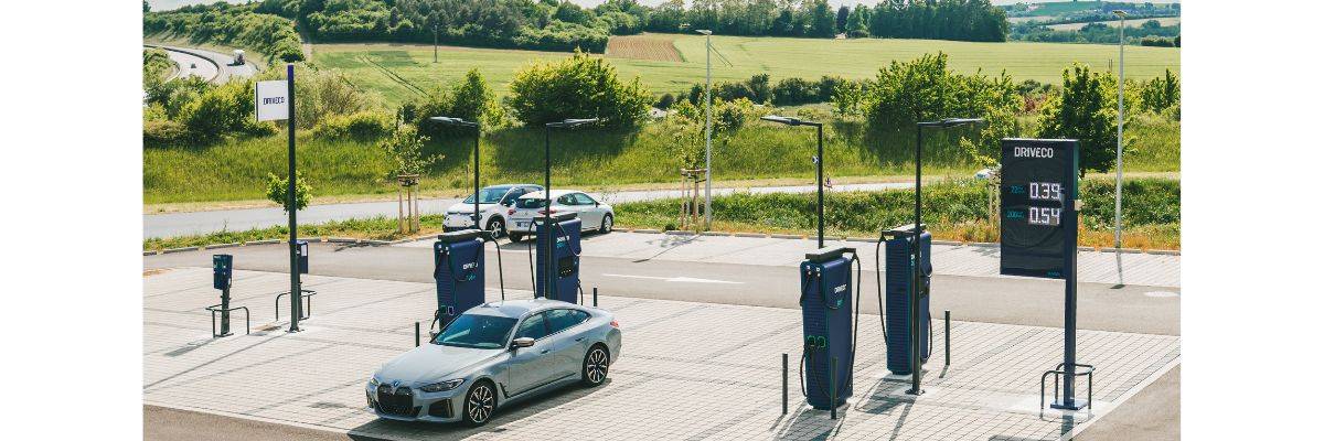 Station de recharge Driveco en plein air, équipée de plusieurs bornes rapides. Une voiture électrique grise est branchée à l’une des bornes.