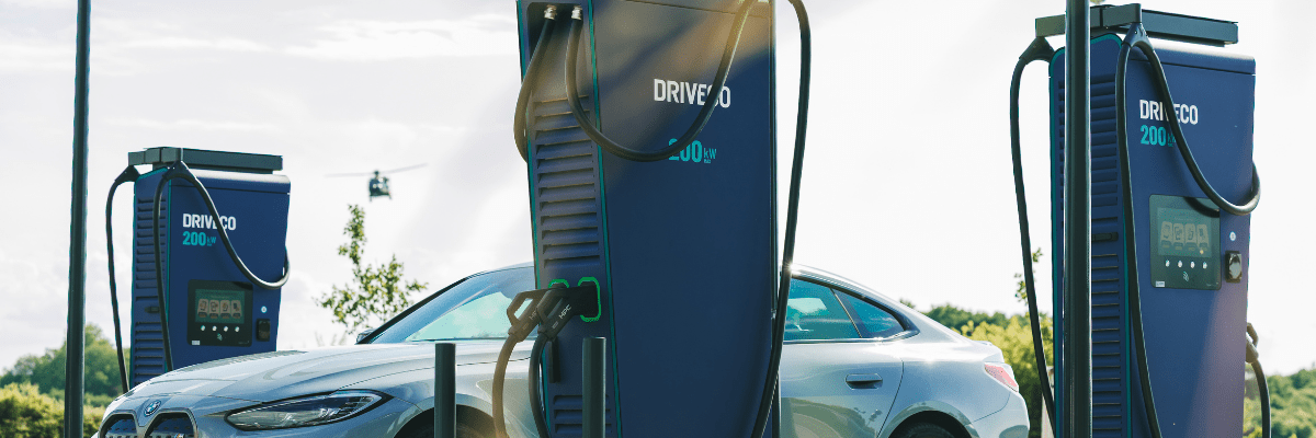 Voiture électrique grise branchée à une borne de recharge rapide DRVECO 200 kW sur un site extérieur, par temps clair.