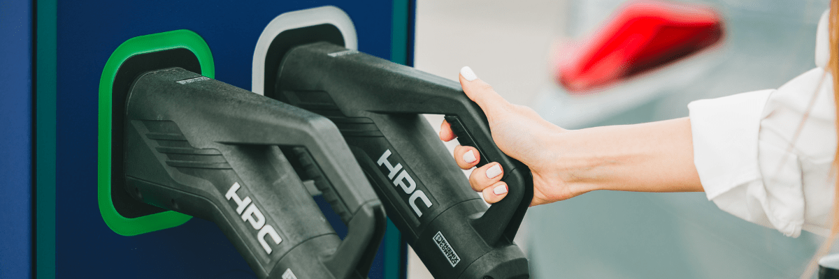Une personne branche un câble de recharge sur une borne pour véhicule électrique.