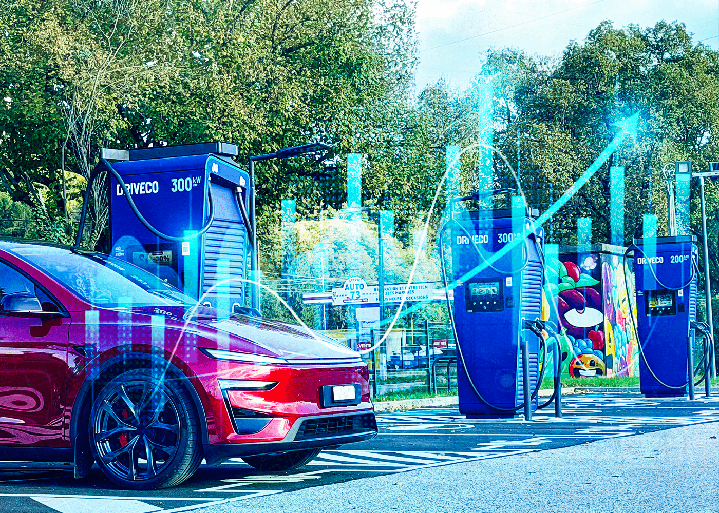Une voiture électrique rouge est stationnée devant plusieurs bornes de recharge DRIVECO de forte puissance (200 et 300 kW).