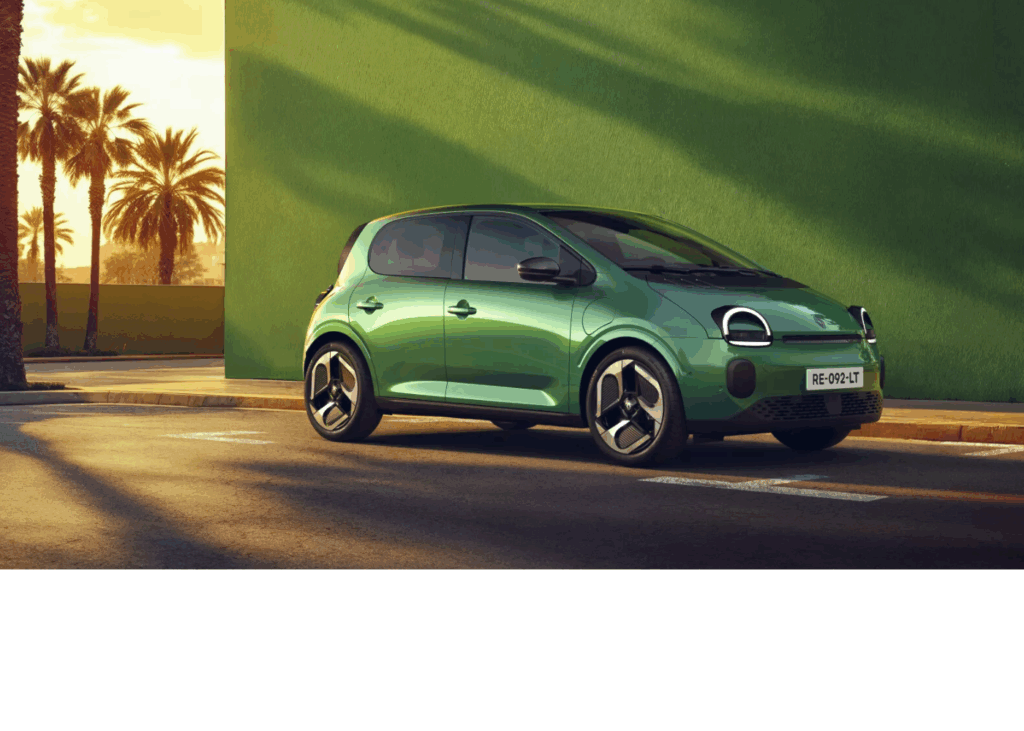 Une petite Twingo E-tech est garée le long d’une rue ensoleillée. Elle est photographiée de profil, avec des jantes noires modernes et des phares avant arrondis.
