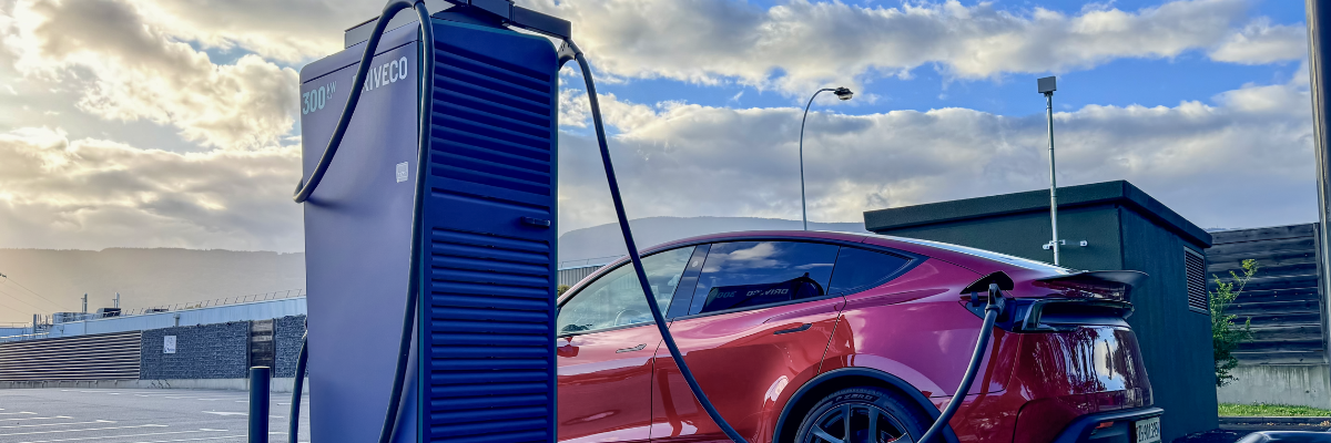 Tesla rouge branchée à une borne de recharge rapide DRIVECO 300 kW dans une station de recharge publique en extérieur.