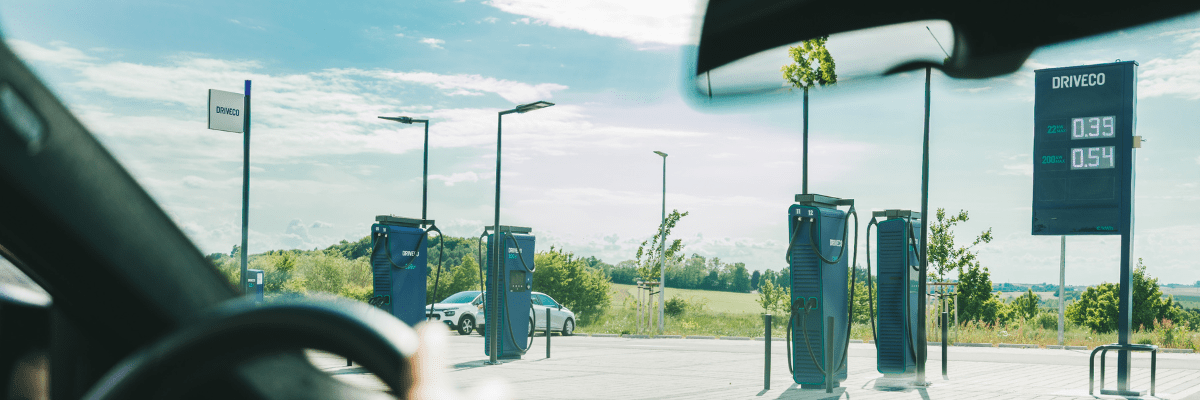 Vue depuis l'intérieur d'une voiture d'une station de recharge pour véhicules électriques DRIVECO en extérieur par temps ensoleillé.
