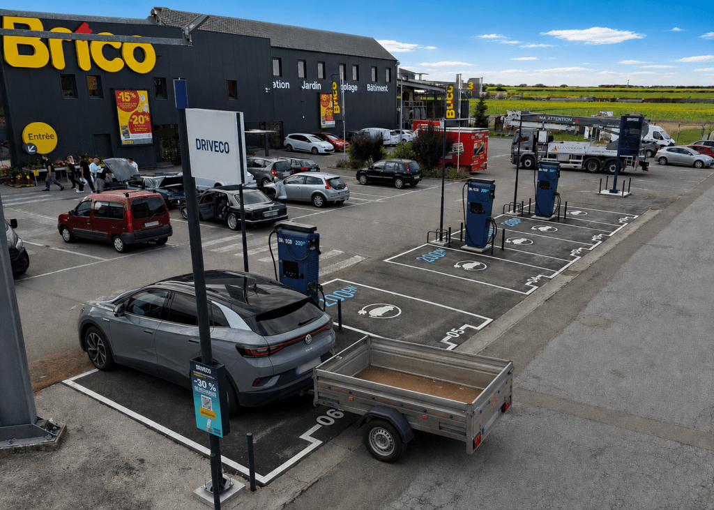 Un véhicule électrique tirant une remorque est stationné sur une place de borne de recharge électrique DRIVECO