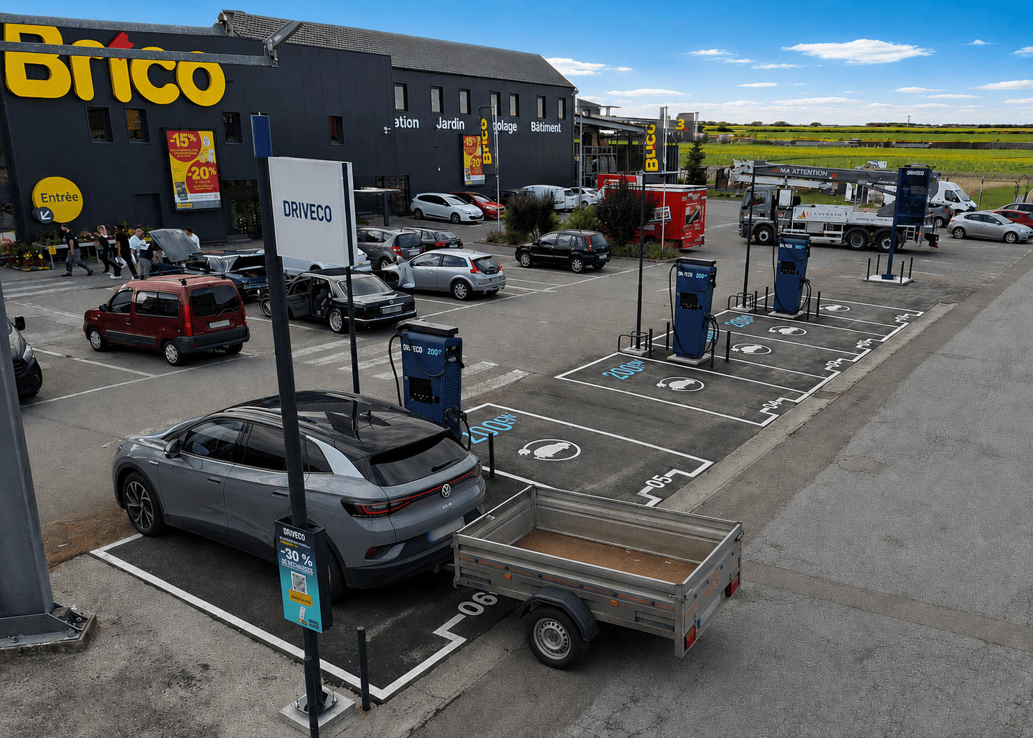Un véhicule électrique tirant une remorque est stationné sur une place de borne de recharge électrique DRIVECO